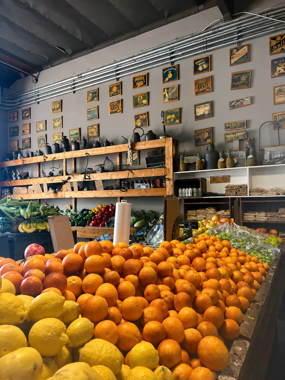 Mountains of fresh oranges and lemons at The Fruit Stand, under a wall of vintage California citrus crate labels